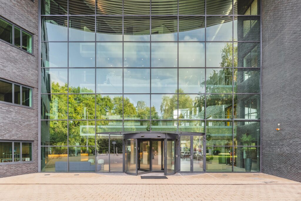 Ingang van een modern kantoorgebouw aan de Prof. W.H. Keesomlaan met een grote glazen gevel en een draaideur.